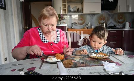 Großmutter füttert ihren Enkel in der Küche. Stockfoto