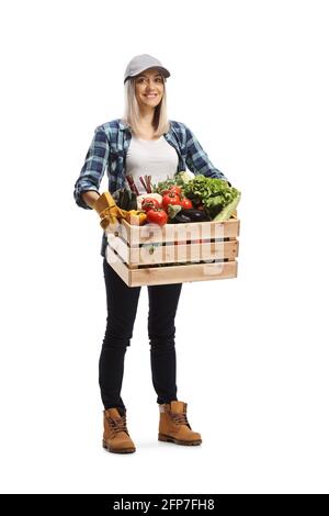 In voller Länge Porträt einer jungen Farmerin mit einem Kiste mit Gemüse und lächelnd isoliert auf weißem Hintergrund Stockfoto
