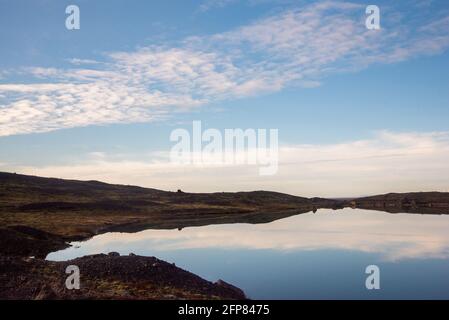 Stimmungsvolle isländische Landschaft mit blauem Himmel und Wolken, die sich widerspiegeln Wasser Stockfoto