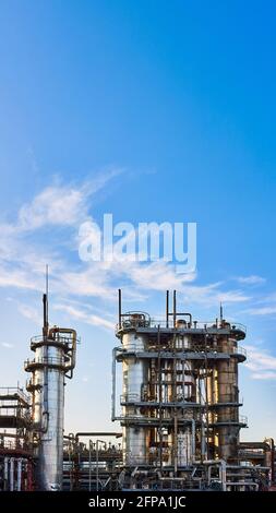 Alte Destillationskolonnen und Reaktoren unter blauem Abendhimmel im Chemiewerk. Außenansicht des silbernen Metalls rostig Enterprise 16x9 Stockfoto