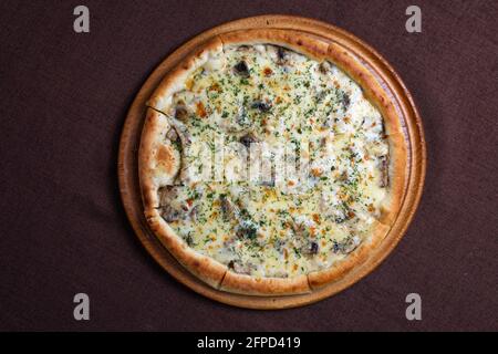 Pizza mit Käse, Pilzen und Kräutern auf einem dicken Teig Stockfoto