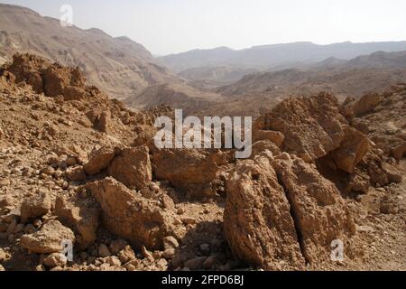 Typische Landschaft, riesige Felsbrocken und raues Gelände und felsiger Boden im trockenen Flussbett von Nahal oder Nachal Tzafit in der trockenen Negev-Wüste, Israel. Stockfoto