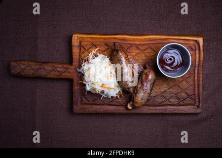 Gegrillte hausgemachte Würste mit Salzkohl auf dem Brett Stockfoto