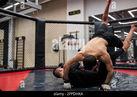 Mixed Martial Artists vor dem Kampf kämpfen zwei kaukasische MMA-Kämpfer auf dem Boden, um sich auf den Wettkampf in der Kampfkunst vorzubereiten Stockfoto