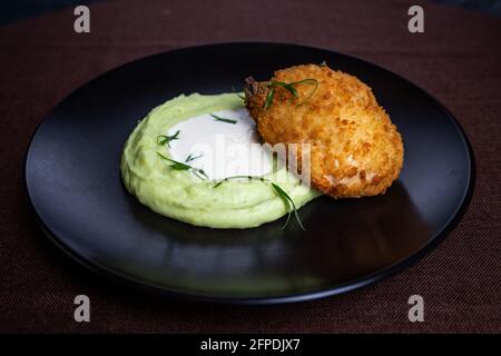 Kiewer Kotelett mit Kartoffelpüree auf schwarzem Teller. Stockfoto