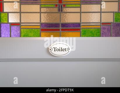 Graue Holztür mit WC-Zeichen Text und bunten Glasmalerei im Gebäude, Nahaufnahme Hintergrundstruktur modernes Design Stockfoto
