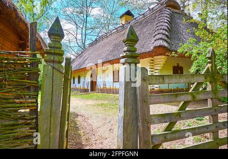 Das alte Holzdickicht zum Anwesen des Schmieds mit weiß getünchten Haus und Weidenzaun, Mamajeva Sloboda Kosakendorf Scansen, Kiew, Ukraine Stockfoto