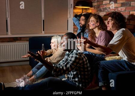 Junge jubelnde Freunde oder Basketball-Fans beobachten Basketball-Spiel im fernsehen zu Hause.Freundschaft, Sport und Unterhaltung Konzept. Junge Menschen sorgen sich um sich Stockfoto