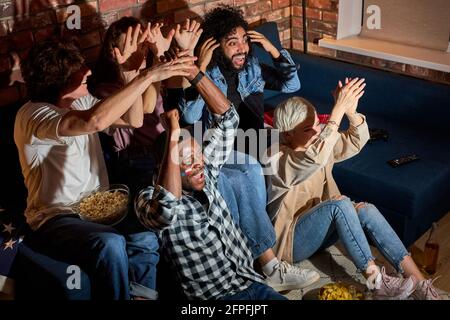 Junge Fußballfans versammelten sich, um zu jubeln, während sie Fußball oder andere Sportspiele zu Hause sahen, Freunde, die auf den Bildschirm des fernsehens jubelten, Spaß hatten, suppo Stockfoto