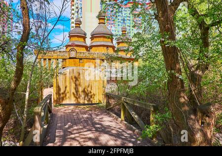 Die Holzbrücke und ein Tor zur alten Holzkirche im Kosakendorf Mamajeva Sloboda, Kiew, Ukraine Stockfoto