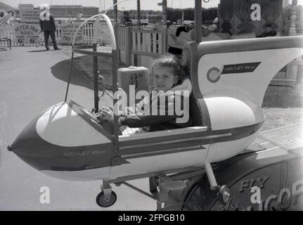 1962, historisch, ein kleines Mädchen, das in einer Vergnügungsfahrt am Meer sitzt, ein Heli-Jet, VII, an der Front im Brighton, W. Sussex, England, Großbritannien. Stockfoto