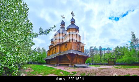 Panorama der Holzkirche der Fürbitte der Jungfrau Maria mit blühenden Obstbäumen um sie herum, Mamajeva Sloboda Kosakendorf, Kiew, Ukraine Stockfoto