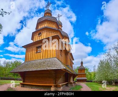 Die malerische Holzkirche der Fürbitte der Jungfrau Maria mit einem Glockenturm im Hintergrund, Mamajeva Sloboda Kosakendorf, Kiew, Ukraine Stockfoto