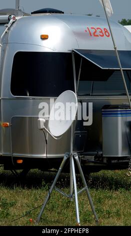 Nur weil Sie weit weg von zu Hause in der Mitte von Nirgendwo sind, bedeutet nicht, dass Sie nicht Hunderte von Kanälen über Ihre Satellitenschüssel haben können. Dieser Airstream ist bei der Airstream-Rallye im Juni 2005 in Springfield, Missouri. Stockfoto