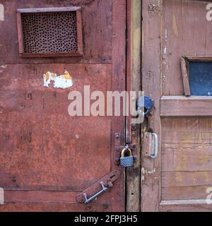 Alte Scheunentüren, mit abblätternder Farbe, mit zwei großen Metallschlössern darauf. Muster Stockfoto