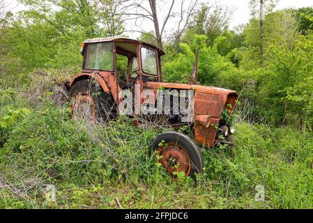 Alte rostige vintage verlassenen Traktor auf einem Feld mit hohem Gras bewachsen. Stockfoto