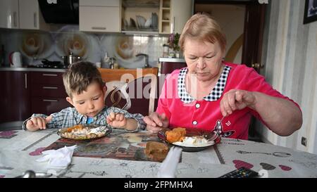Großmutter füttert ihren Enkel in der Küche. Stockfoto