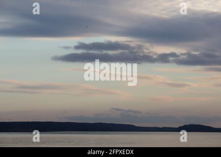 Pastellrosa Wolken über dem Klang vor dunklem, silhouettierten Land Stockfoto