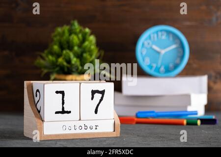 Oktober. Oktober 17 Holzwürfelkalender mit unscharfen Objekten auf dem Hintergrund. Stockfoto