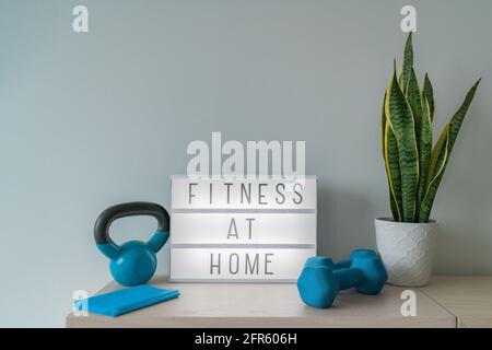 Fitness zu Hause Lichtschild mit Kettlebell Gewicht und Hanteln, Widerstandsbänder für Pilates Online-Klasse. Trainieren Sie drinnen für Frauen. Stockfoto