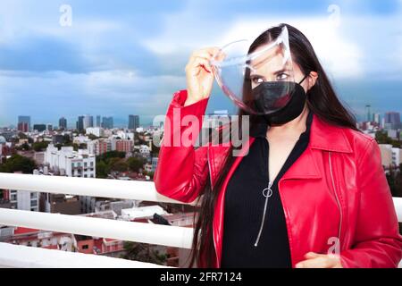 Kaukasische Frau mit Maskenschutz und setzen Plastikmaske auf Ihr Gesicht, um durch Mexiko-Stadt zu gehen Stockfoto