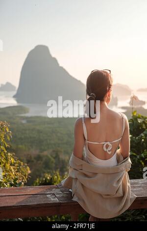 Glückliche Reisende Frau genießen Phang Nga Bucht Aussichtspunkt, allein Touristen sitzen und entspannen in Samet Nang She, in der Nähe von Phuket in Südthailand. Südosten Stockfoto