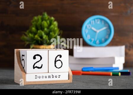 Dezember. Dezember 26 Holzwürfelkalender mit unscharfen Objekten auf dem Hintergrund. Stockfoto