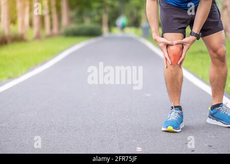 Junger erwachsener Mann mit Muskelschmerzen während des Laufens. Läufer haben Knieschmerzen durch Läufer Knie- oder Patellofemorales Schmerzsyndrom, Osteoarthritis Stockfoto