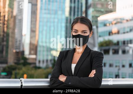 Asiatische Geschäftsfrau oder Immobilienmakler zuversichtlich Porträt tragen Gesichtsmaske für Coronavirus-Prävention im städtischen Stadthintergrund Stockfoto