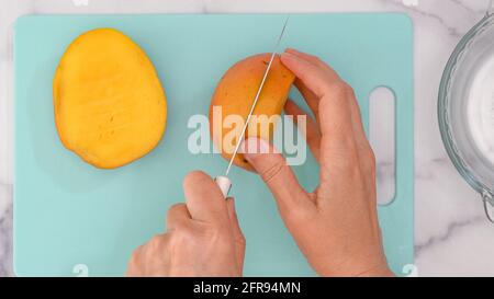 Frau Hände schneiden frische reife Mango, Nahaufnahme von oben Stockfoto