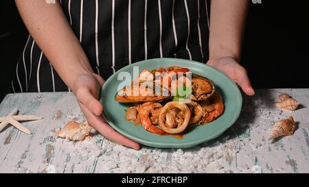 Nahaufnahme der Hände, die einen Teller mit thailändischem Essen halten, Meeresfrüchte-Rührpulver Stockfoto