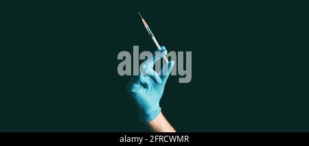 Impfstoffspritze mit Coronavirus, die von einem Arzt oder einer Krankenschwester in blauer Farbe gehalten wird Medizinischer psa-Handschuh vor schwarzem Hintergrundbanner Stockfoto