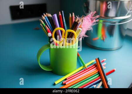 Buntstifte in einem grünen Kreis auf dem blauen Tisch. Viele verschiedene Buntstifte. Schreibwaren. Stockfoto