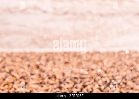 Abstrakte Natur Sommer oder Frühling Meer Meer Hintergrund. Kleine Wellen auf der goldenen, warmen Wasseroberfläche verwischen sich in Bewegung mit Bokeh-Lichtern vom Sonnenuntergang. Urlaub Stockfoto