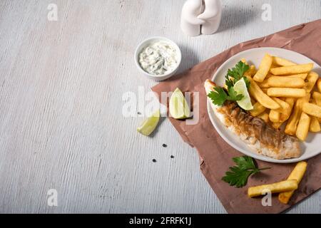 Fisch und Chips mit Zitrone, Petersilie und Sauce Stockfoto