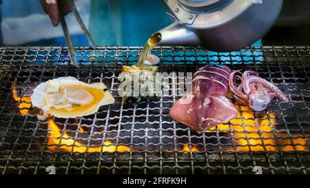 Ein Straßenverkäufer bereitet Meeresfrüchte auf einem Grill auf der Enoshima-Insel in Japan zu. Stockfoto