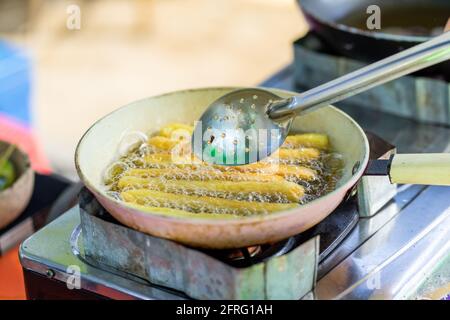 Churros werden in einer flachen Pfanne gebraten. Stockfoto