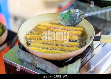 Churros werden in einer flachen Pfanne gebraten. Stockfoto