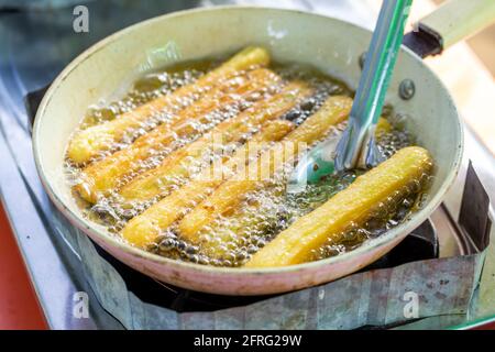 Churros werden in einer flachen Pfanne gebraten. Stockfoto