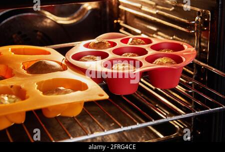 Formen mit fertig gebackenen Muffins mit sonnengetrockneten Tomaten im Ofen. Stockfoto