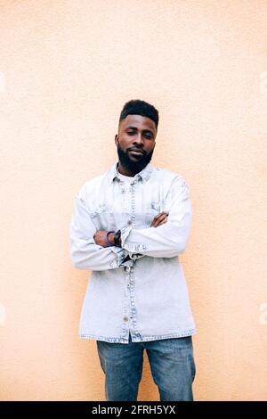 Porträt eines ernsthaften jungen afrikanischen Mannes in Denim-Hemd auf pastellfarbenem Hintergrund. Stockfoto