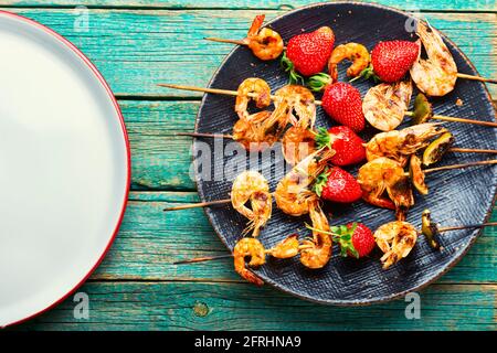 Leckere gegrillte Garnelen auf Holzspießen mit Erdbeeren.geröstete Garnelen Stockfoto