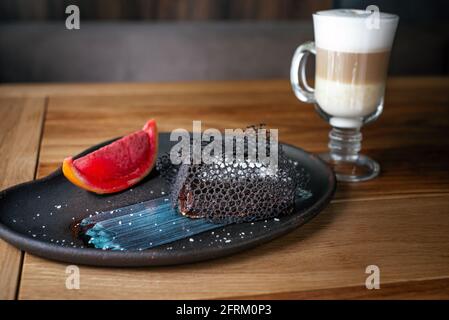 Erstaunliches Schokoladendessert mit Eis und dreilagiger Latte. Schickes Dessert, Schokoladenbrownie. Süße Bäckerei und Dessert auf Holzhintergrund. Stockfoto