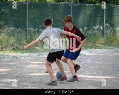 Zwei Teenage-Jungen, die auf einem Dusty-Feld Fußball spielen. Stockfoto