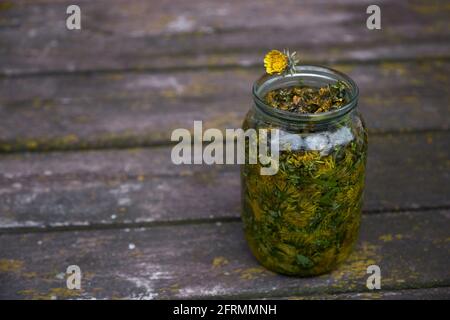 Natürliches Wellness-Konzept. Die Dandeliontinktur ist ein natürliches homöopathisches Mittel zu Hause. In Alkohol infundiert. Rustikaler Hintergrund Stockfoto