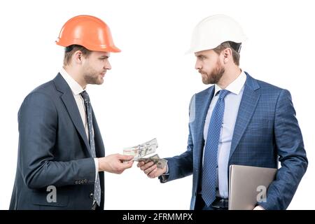 Investoren Männer in Anzug und Schutzhelm geben oder nehmen Geld und halten Computer, Investitionen Stockfoto