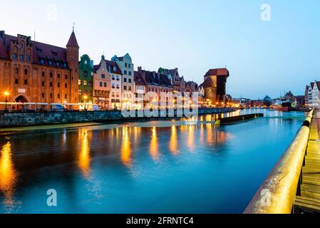 Blick auf die Stadt Danzig bei Nacht am Fluss. Blick auf den berühmten Kran und die Fassaden der alten mittelalterlichen Häuser an der Promenade in Danzig Stadt. Polen. Stockfoto