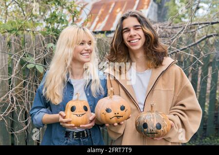 Ein paar lachende Teenager mit halloween-Kürbissen, die Spaß haben Stockfoto