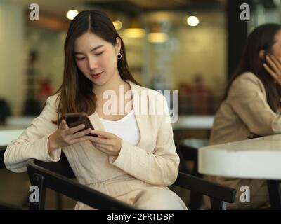 Porträt einer Geschäftsfrau mit Smartphone während des entspannten Sitzens in einem Meeting Zimmer Stockfoto