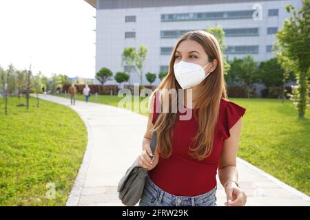 Schöne junge Geschäftsfrau trägt FFP2 KN95 Gesichtsmaske gehen Zur Seite schauen Stockfoto